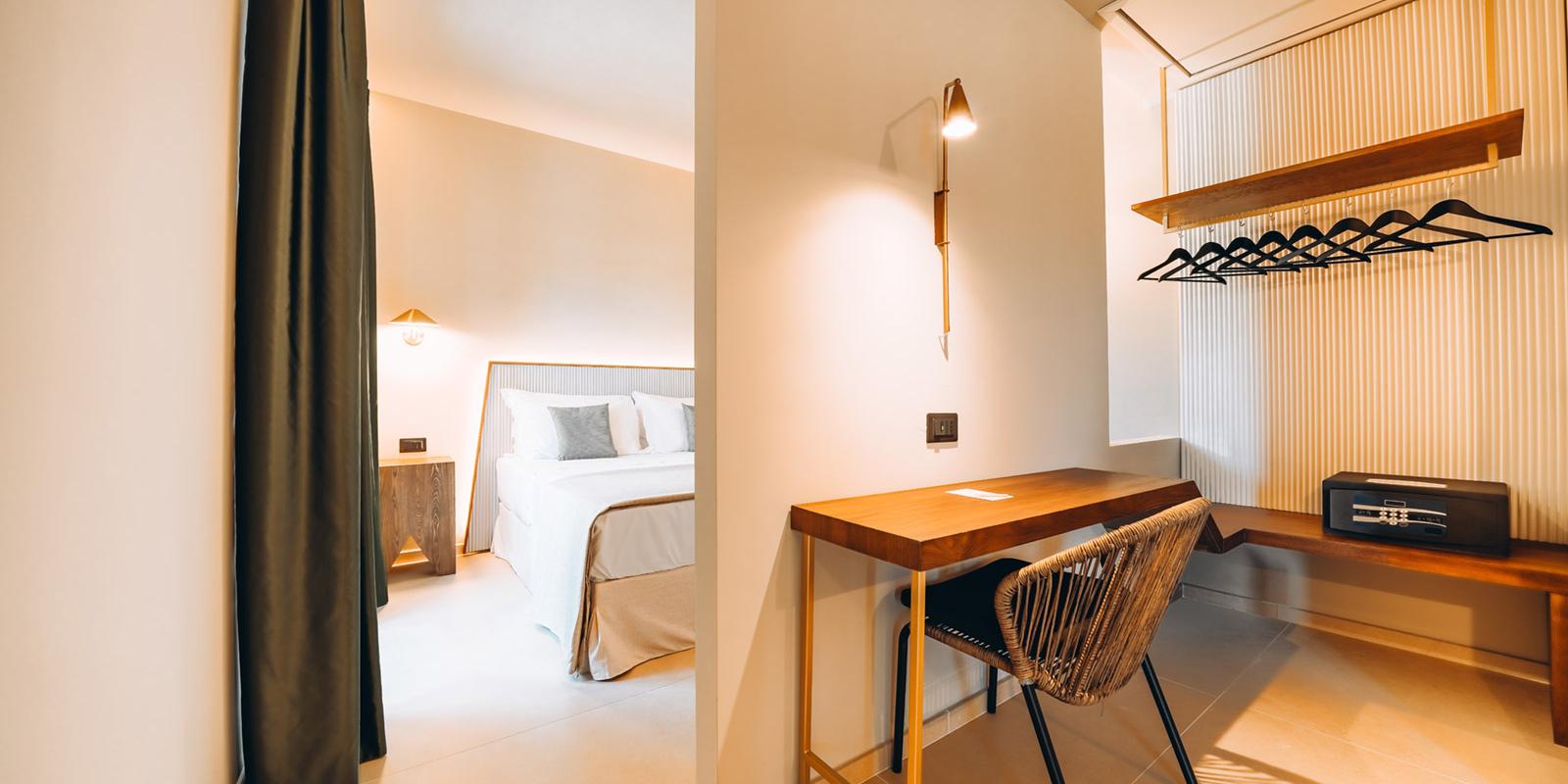 Camera moderna con letto, scrivania, sedia e armadio aperto con cassaforte.
