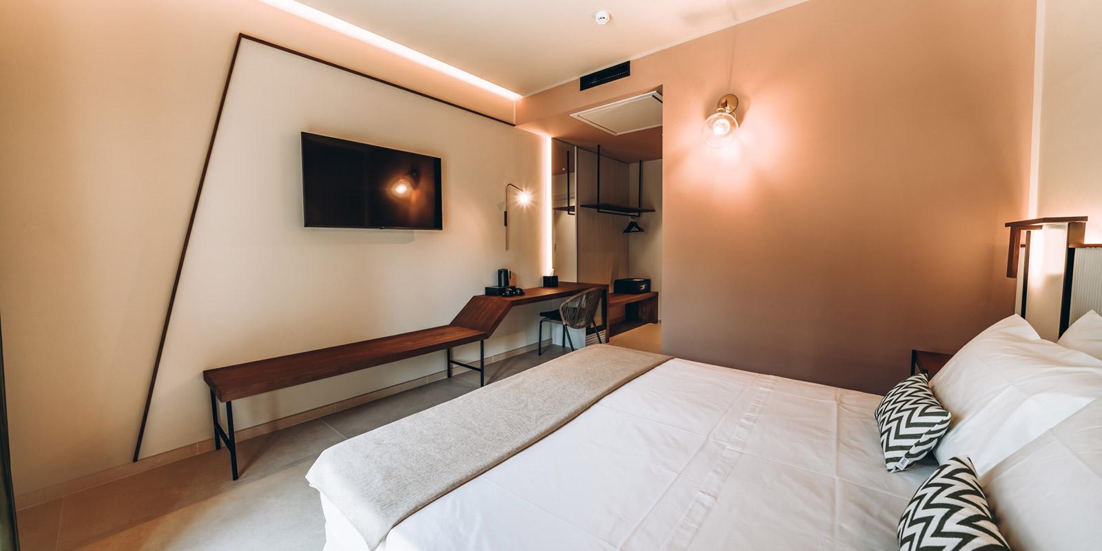Camera moderna con letto matrimoniale, TV a parete e arredi eleganti.