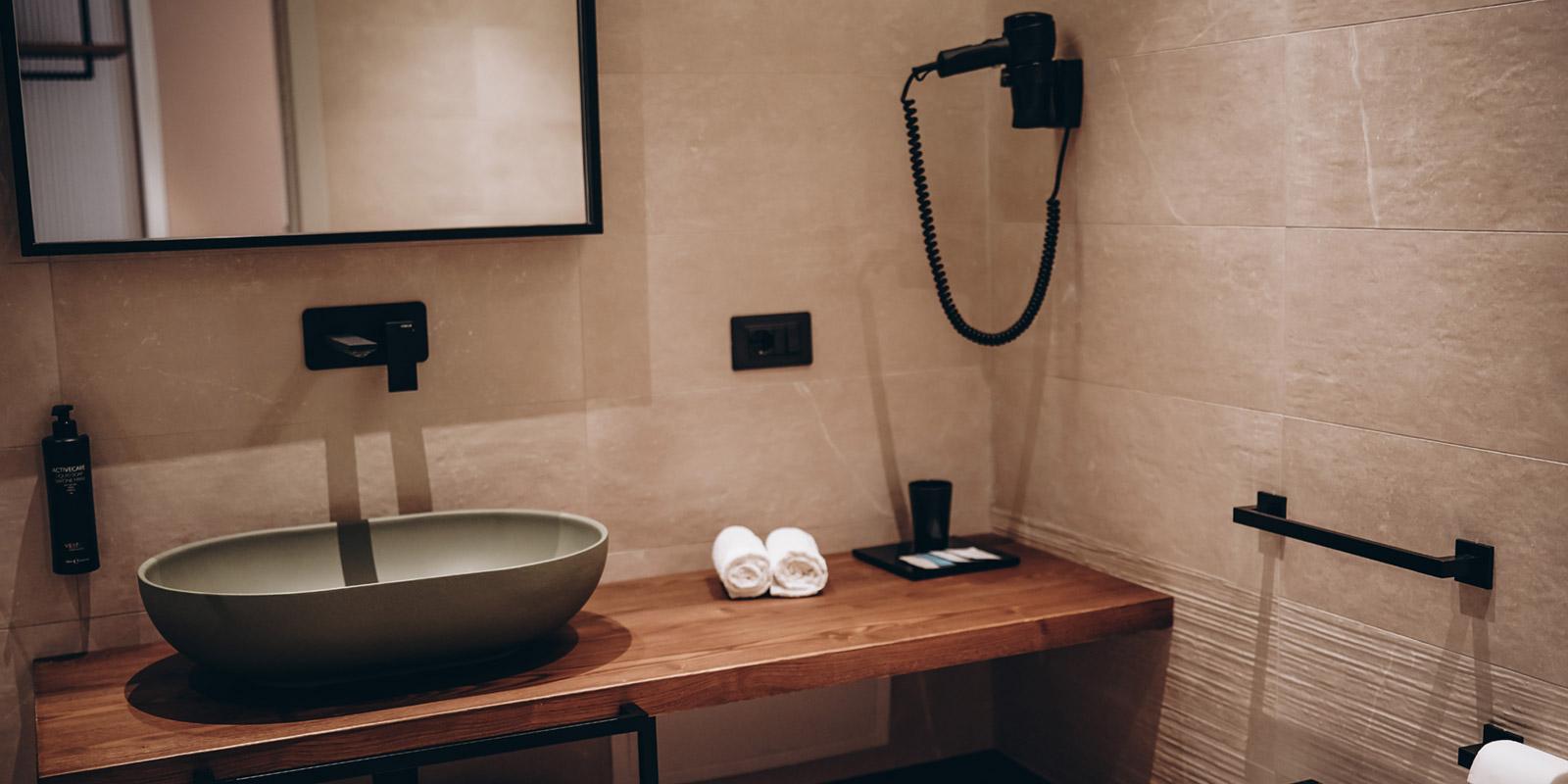 Bagno moderno con lavabo ovale, specchio, asciugacapelli e accessori eleganti.