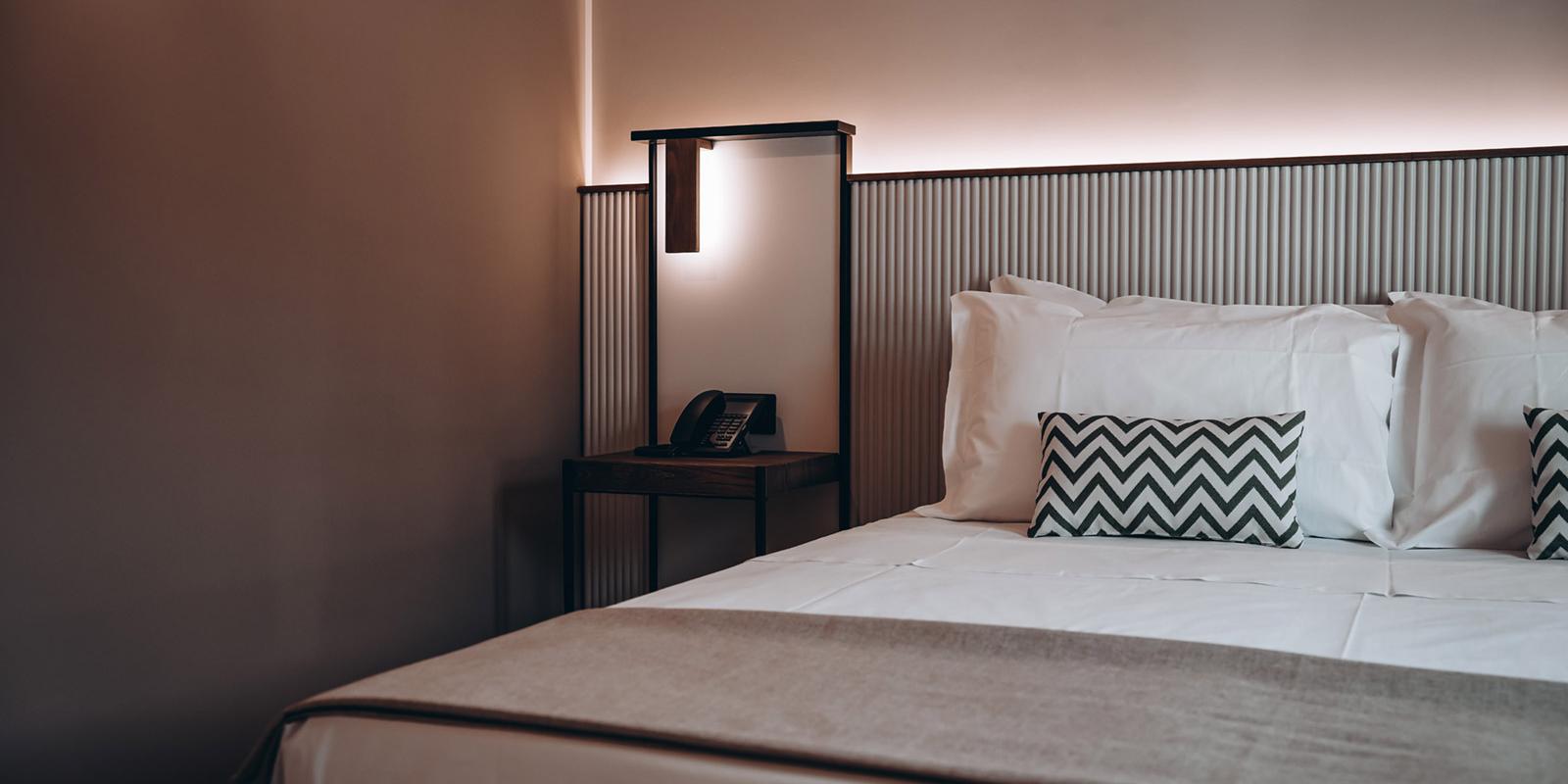 Camera moderna con letto matrimoniale, cuscini a zigzag e telefono sul comodino.