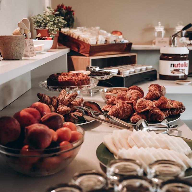Buffet per colazione con croissant, frutta, dolci e crema spalmabile.